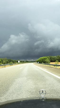 Sunny road with stormy skies ahead